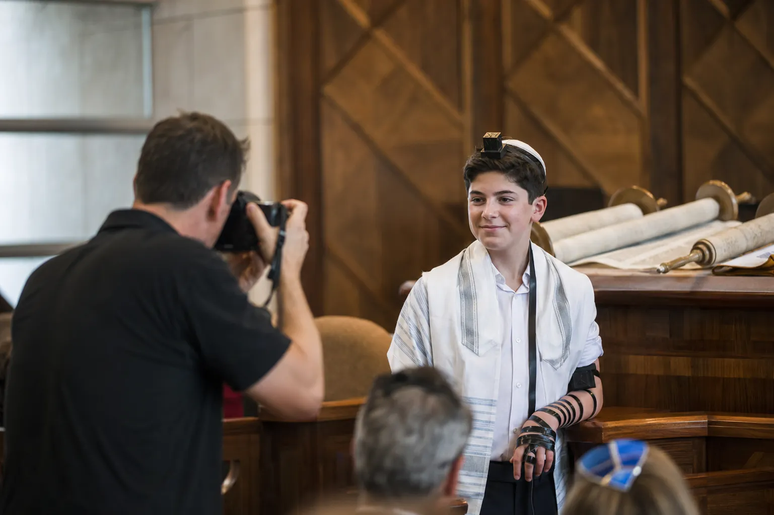 צלם לבר מצווה מצלם את הנחת התפילין בעלייה לתורה בבית הכנסת